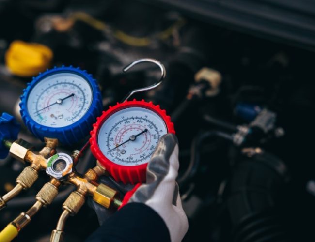 Close up hand of Mechanics inspect and check the refrigerant and fill the car air conditioner. Worker service car air conditioner.