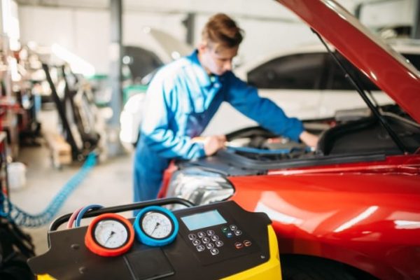 Mechanic pumps freon into the car air conditioning system. Conditioner inspection in auto-service